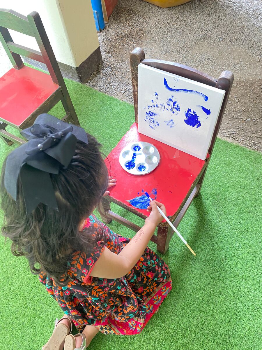 A young pupil painting at a small easel