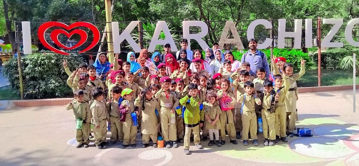 Montessori cadets and their teachers gathered at the Karachi Zoo sign