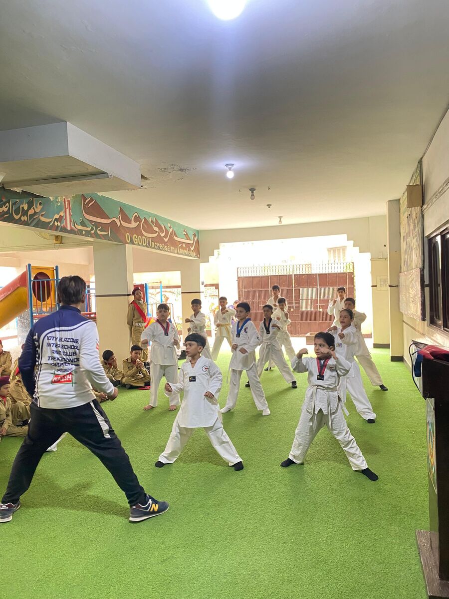 Pupils in white uniforms practising taekwondo in the school hall